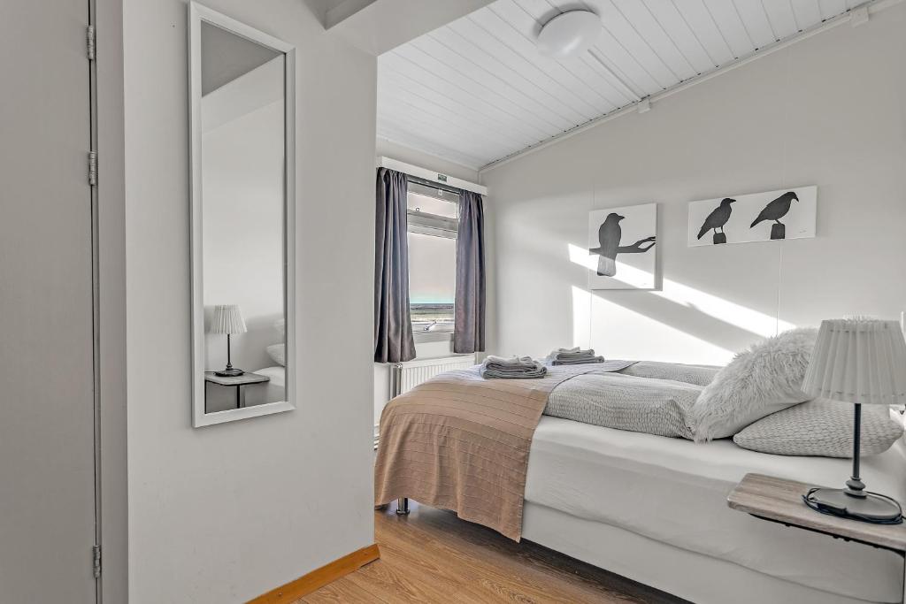 a white bedroom with a bed and a window at Guesthouse Vatnsholt in Vatnsholt