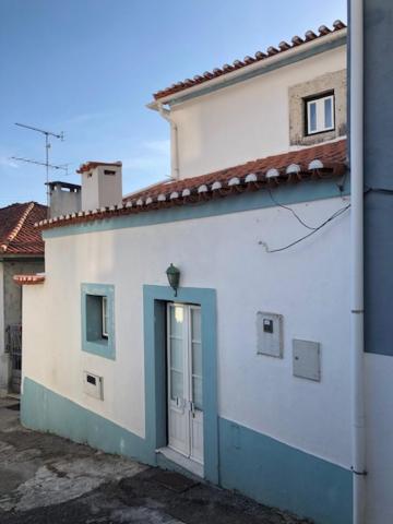 a white building with a blue door on the side at Typical small house near Lisbon in Oeiras