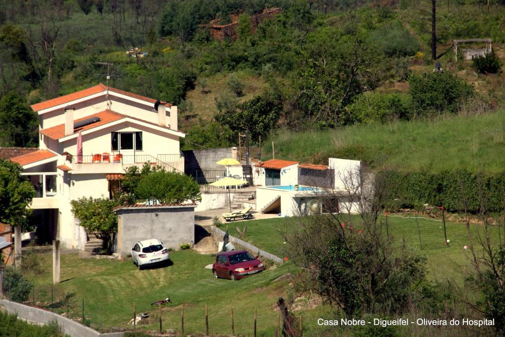 a house with two cars parked in a yard at Casa Nobre SERRA DA ESTRELA in Digueifel