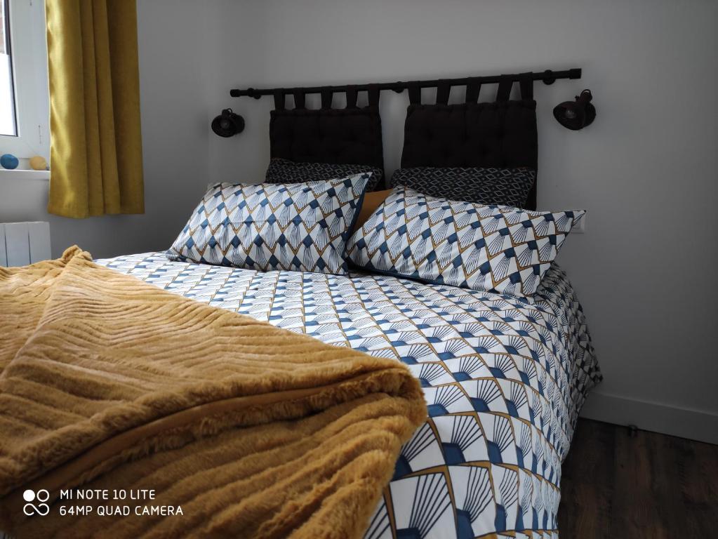 a bed with a black and white comforter and pillows at L' ALBATROS vue sur le port in Fécamp