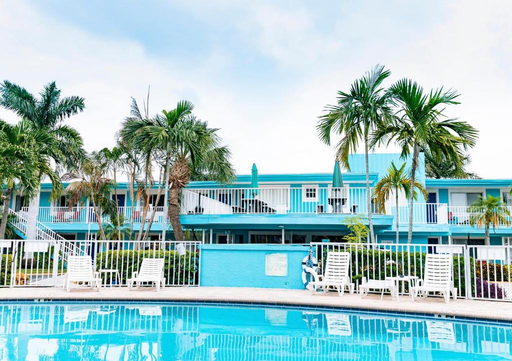 a pool with chairs and palm trees in front of a building at Bayside Inn and Marina in St. Pete Beach