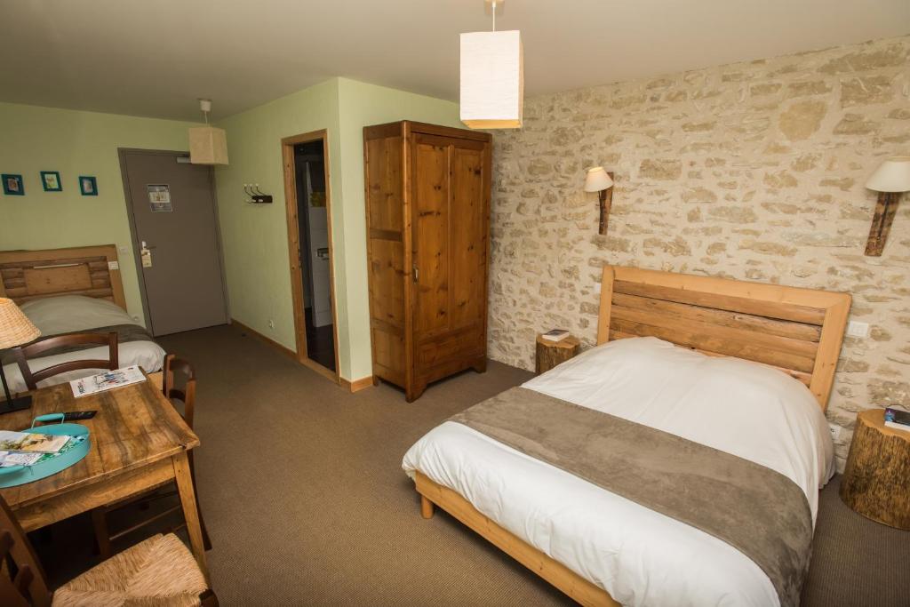 a bedroom with a bed and a table in a room at Auberge le Sabot de Vénus in Méaudre