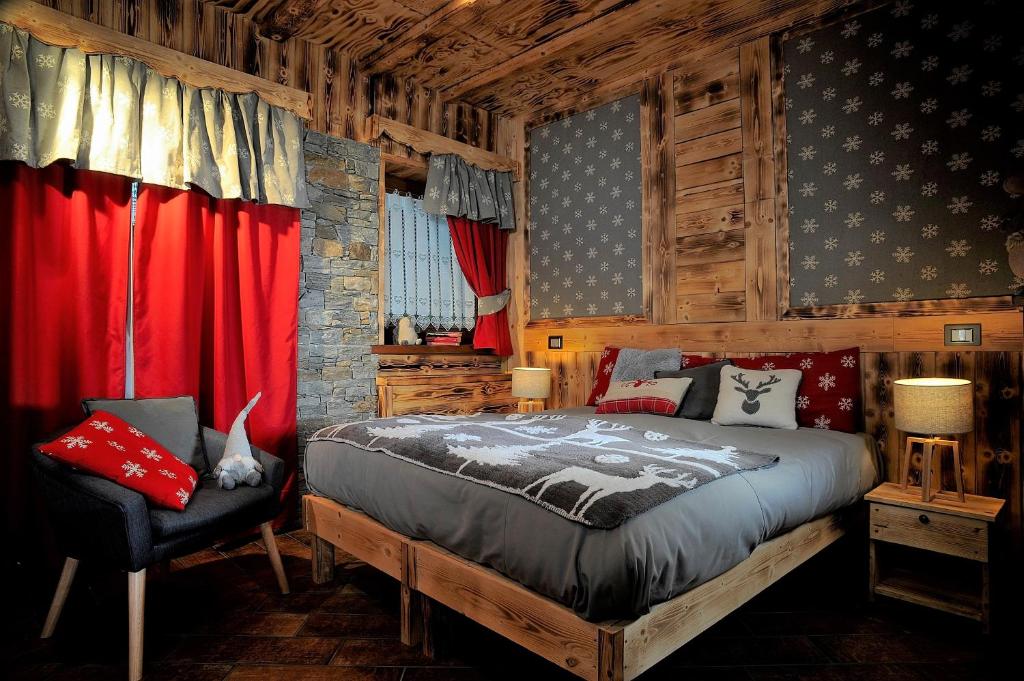 um quarto com uma cama, uma cadeira e cortinas vermelhas em Aparthotel Foyer d'antan SUITE con caminetto hammam o vasca idromassaggio em Brusson