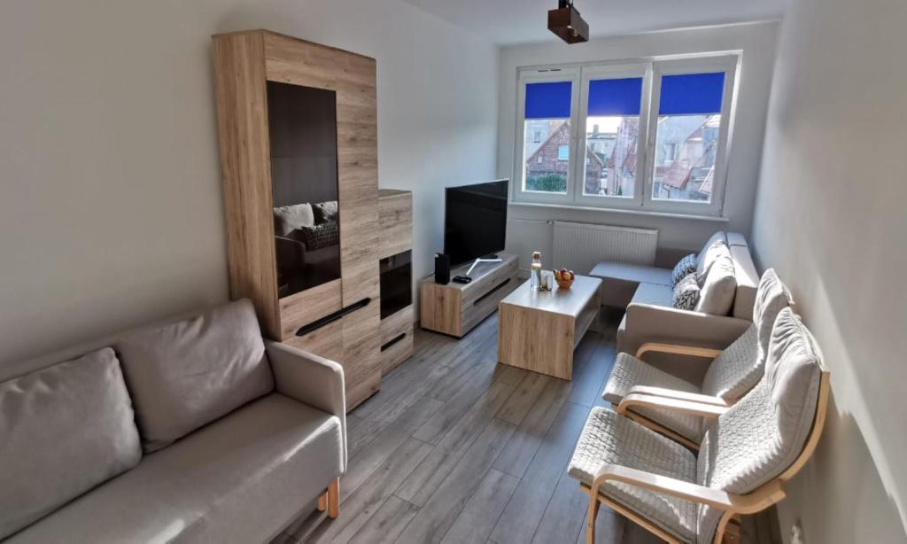a living room with a couch and chairs and a tv at Apartament Highway To Hel in Hel