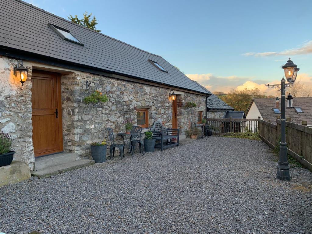 a stone building with tables and chairs outside of it at The Reindeer Retreat Buttercup Twin in Kidwelly