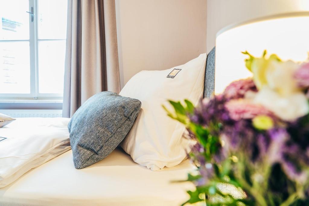 Una cama con almohadas blancas y flores. en Wachau-Living, en Dürnstein