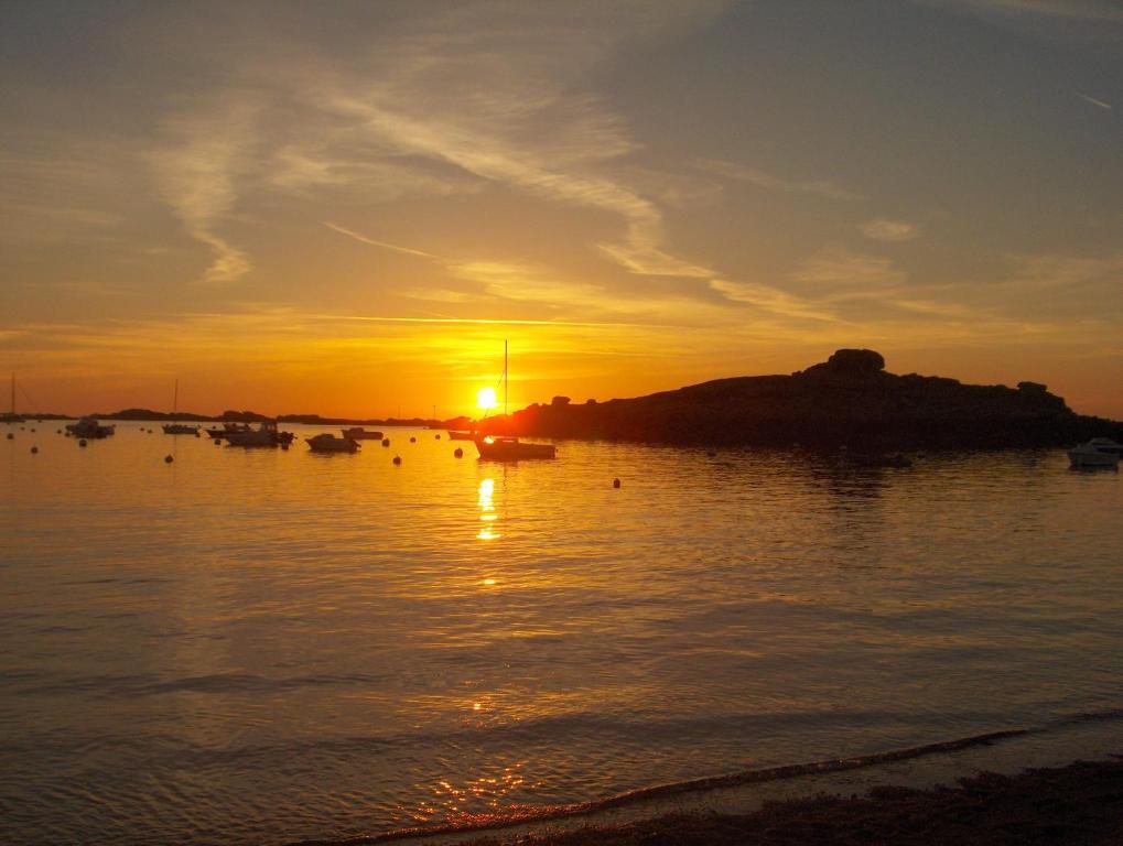 einen Sonnenuntergang über einem Wasserkörper mit Booten in der Unterkunft Hotel De La Mer in Trégastel