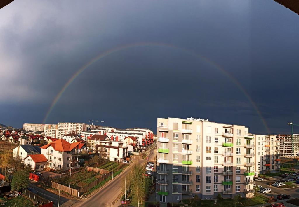 a rainbow in the sky over a city with buildings at Smart Chic Brasov in Braşov