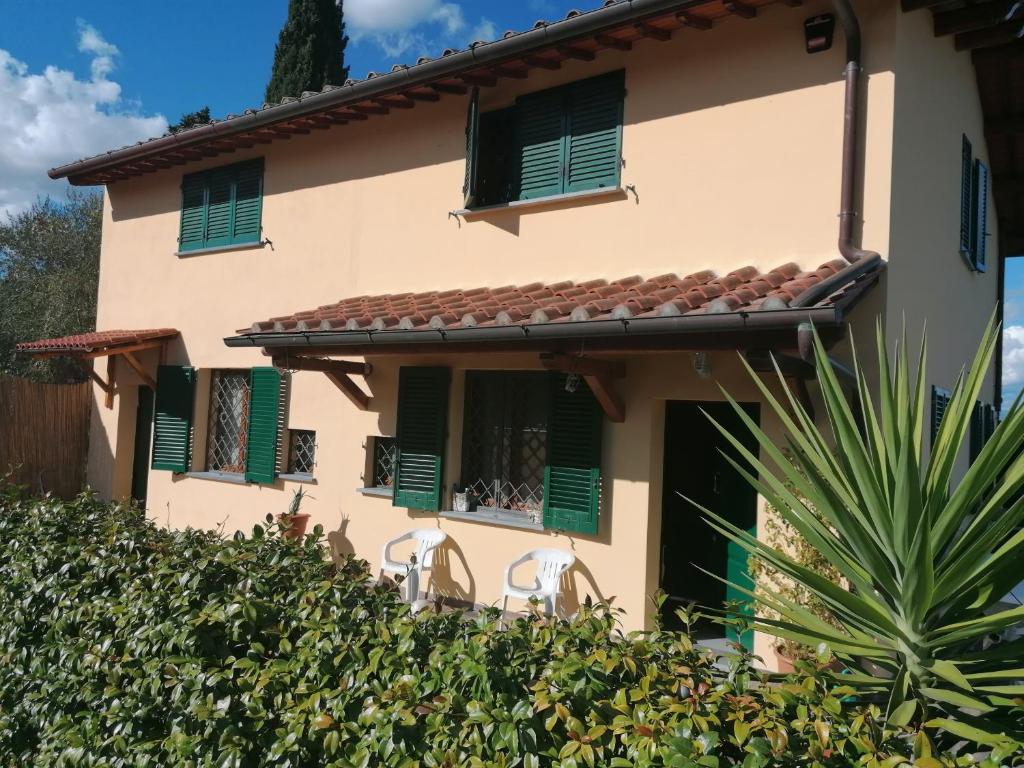 una casa con finestre con persiane verdi e una siepe di La Casa delle Rondini a Montelupo Fiorentino