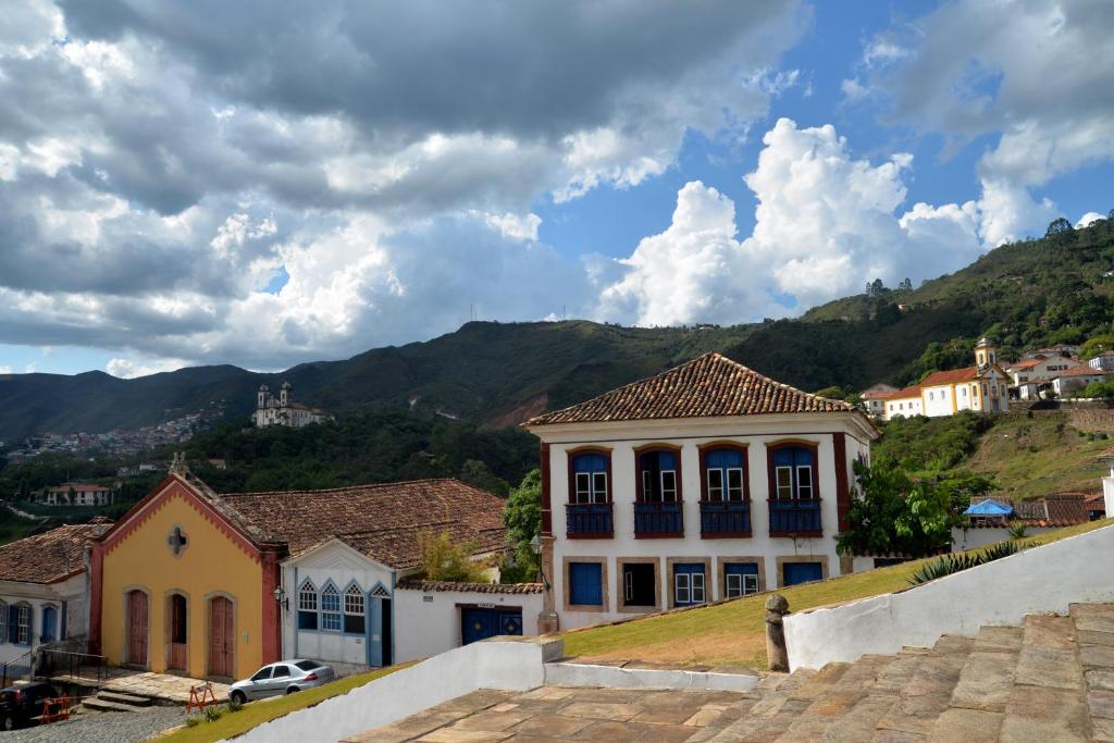 una casa en una colina con montañas en el fondo en Pouso do Chico Rey en Ouro Preto