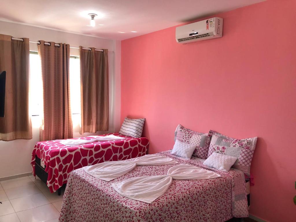 um quarto com duas camas e paredes cor-de-rosa em Pousada Sol Nascente em Barreirinhas