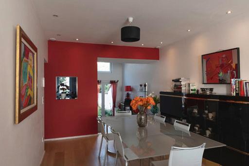 une salle à manger avec une table et un mur rouge dans l'établissement Modern duplex with garden, à Bruxelles