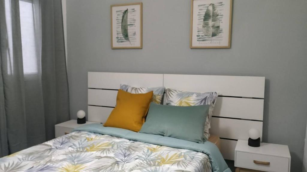 Schlafzimmer mit einem Bett mit gelben und blauen Kissen in der Unterkunft Azvalia - Santi y María in El Puerto de Santa María
