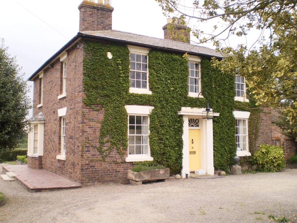 una casa cubierta de hiedra con una puerta amarilla en Duken Courtyard Cottage, en Bridgnorth