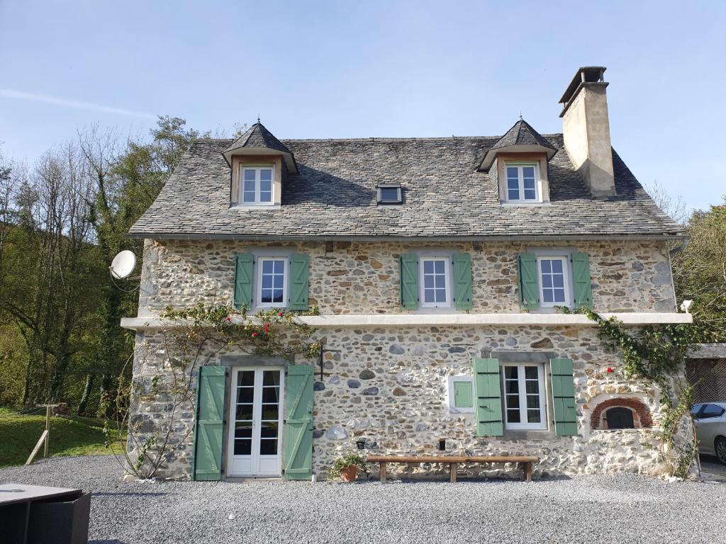 uma casa de pedra com persianas verdes e um banco à frente em Au Nid de Caroline gîte 4 étoiles em Arette