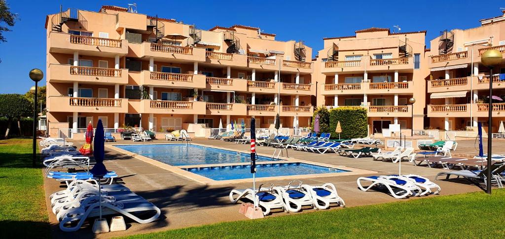 un hotel con piscina, sillas y un edificio en Apartamento Serendipia Resort Cala Bona @Mallorca, en Son Servera