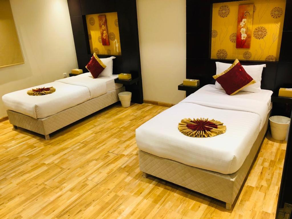 two beds in a room with wooden floors at أول سويت in Riyadh