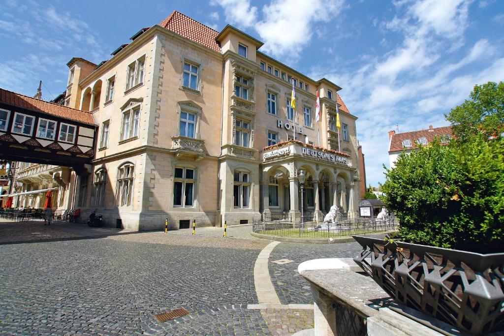 ein großes Gebäude auf einer Straße mit Bänken davor in der Unterkunft Hotel Deutsches Haus in Braunschweig