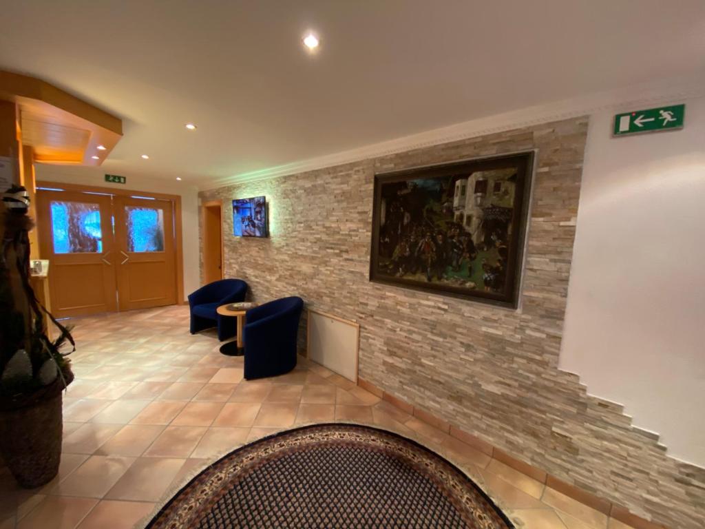 a lobby with a stone wall and blue chairs at Chasa Monthani in Ischgl