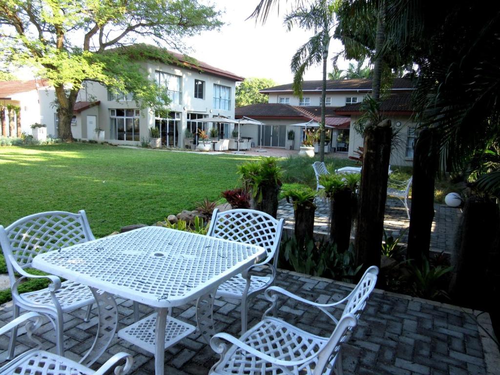 una mesa blanca y sillas en un patio en Elegant Lodge & Conference Center, en Pongola