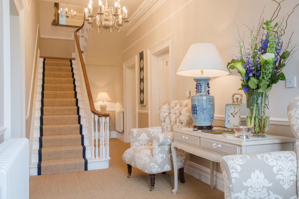 a living room with a table and a chair and stairs at Grays Boutique B&B in Bath