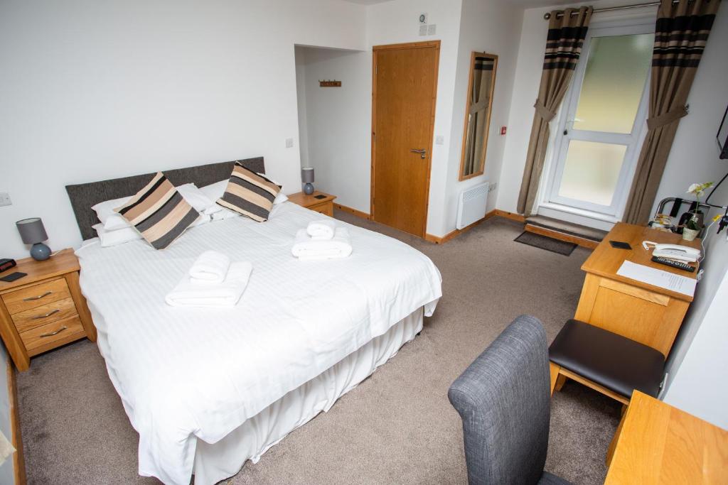 a bedroom with a large white bed and a desk at The Windmill Inn in Watchet