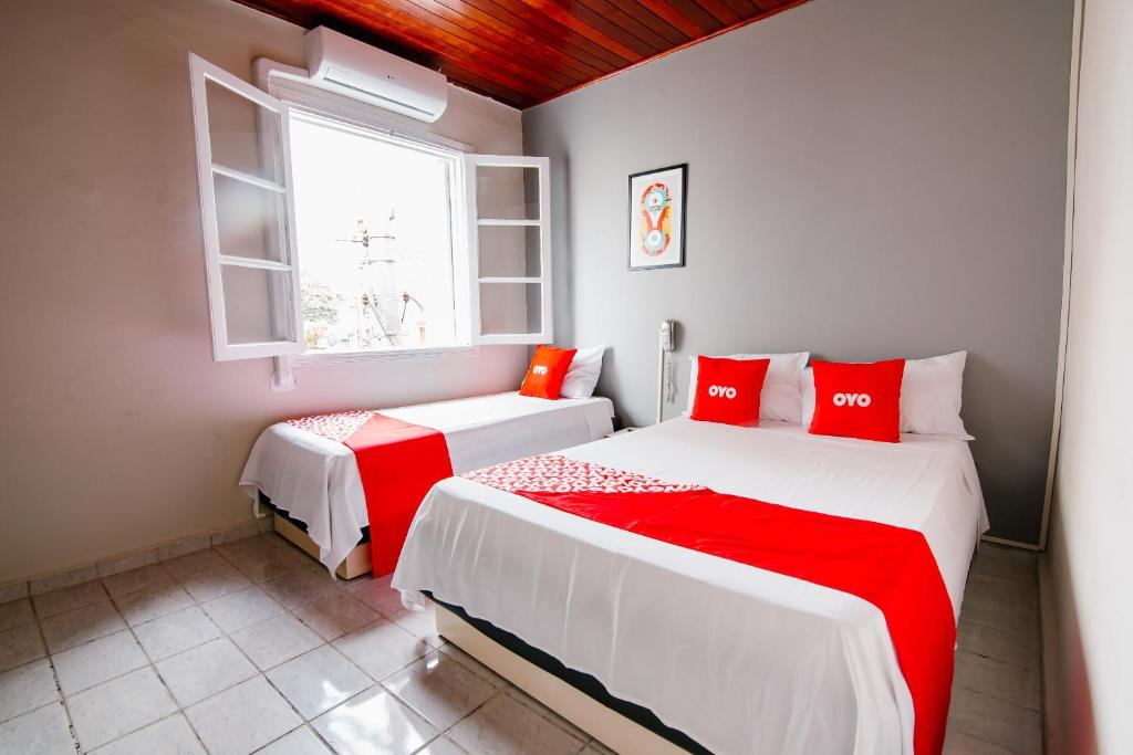 um quarto com 2 camas com lençóis vermelhos e brancos em OYO Hotel Castro Alves, São Paulo em São Paulo