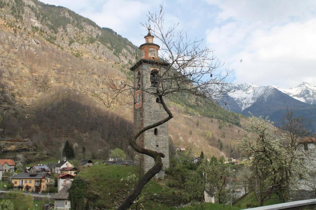 a tall tower with a tree in front of a mountain at tana del paradiso due in Baceno