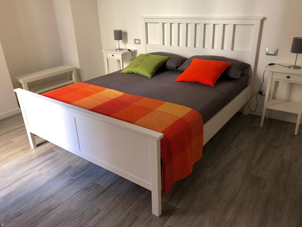 een wit bed met twee kleurrijke kussens erop bij AM's Apartment in La Spezia