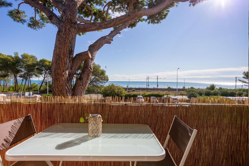 Appartement Marineland Sea View في أنتيب: طاولة وكراسي مع شجرة وسياج