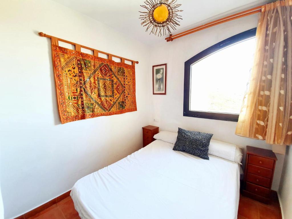 1 dormitorio con cama blanca y ventana en Monte Oiz Slow&Relax by ERB Alojamientos, en Sierra Nevada