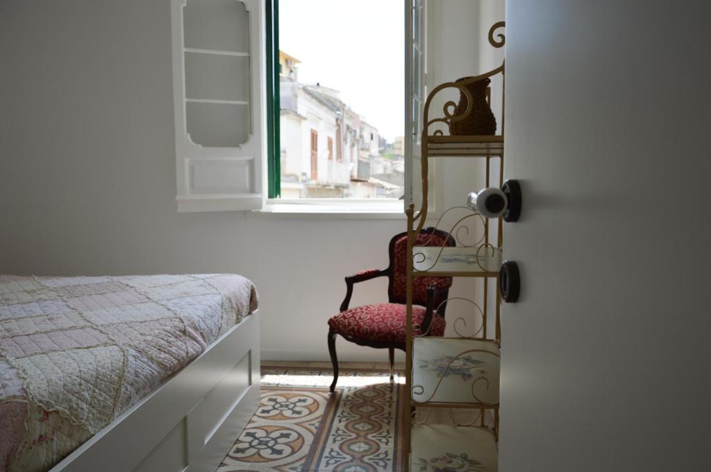 a bedroom with a chair and a bed and a window at Parva Domus in Modica