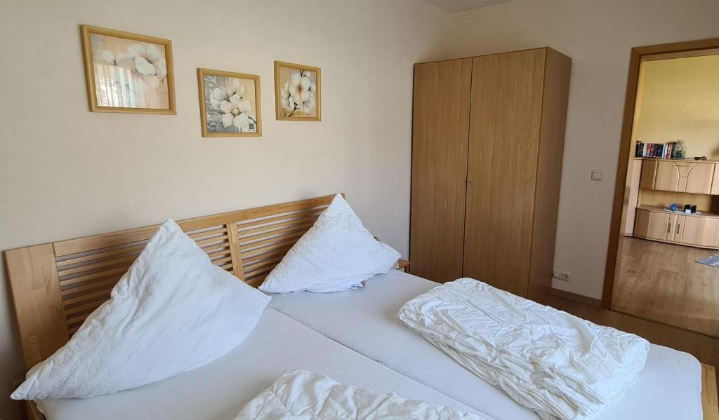 um quarto com uma cama com lençóis brancos e almofadas em Ferienwohnung E. Storm em Kellenhusen