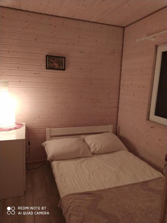 um pequeno quarto com uma cama numa parede em Domek Pralinka nad jeziorem - "Ostoja Penderoza" em Wolin