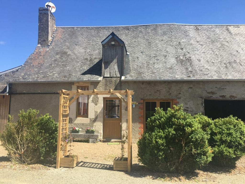 an old house with a wooden doorway in front of it at Gite a la ferme in Rouessé-Vassé