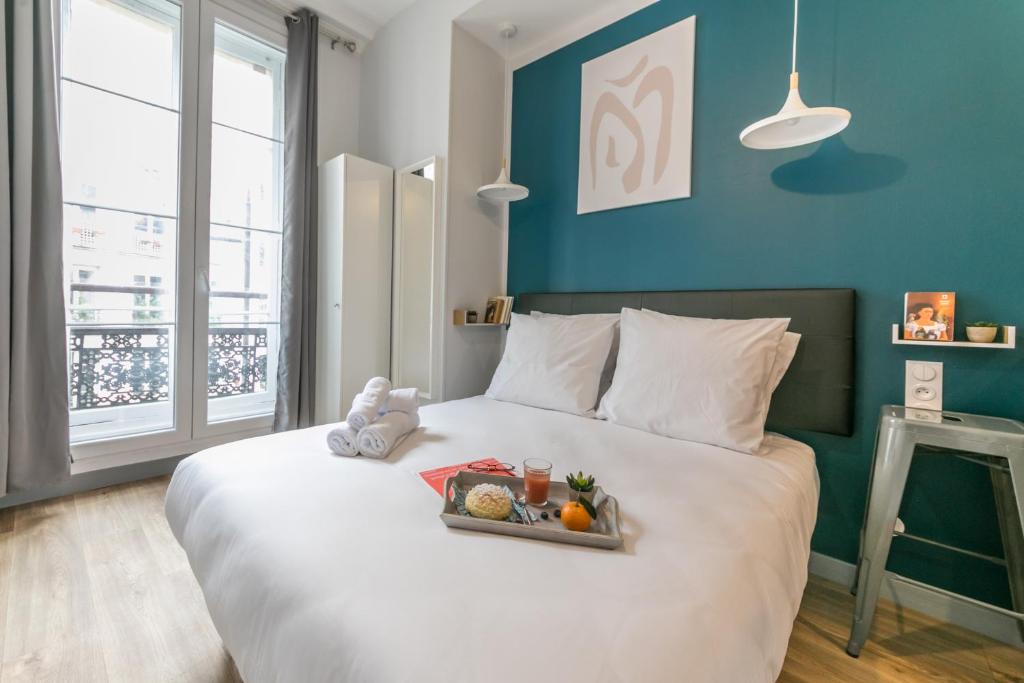 ein großes weißes Bett mit einem Tablett mit Essen drauf in der Unterkunft Apartments WS Louvre - Richelieu in Paris