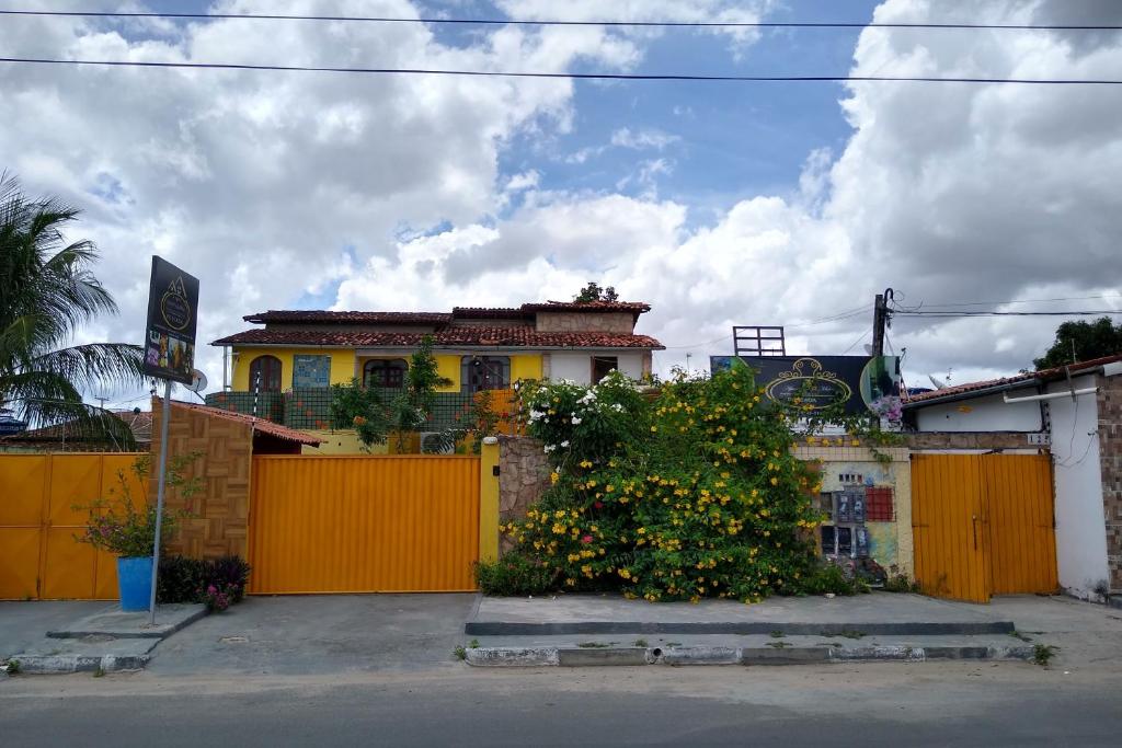 a house with a yellow fence and a bush at Apart Fraga Maia in Feira de Santana