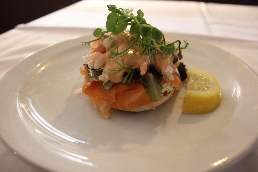 a white plate with a piece of fish and a lemon at The Windmill Inn in Watchet