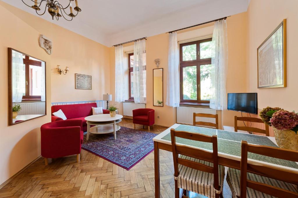 a living room with a red couch and a table at Apartamenty Pod Aniołami in Krakow