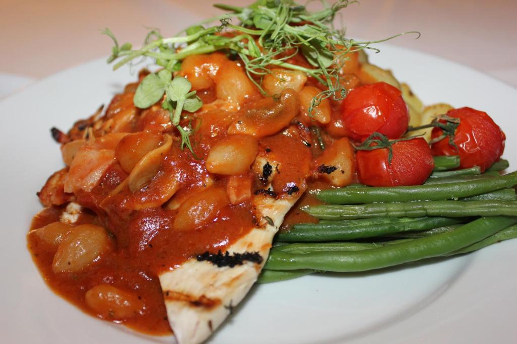 a plate of food with chicken with tomatoes and green beans at The Windmill Inn in Watchet