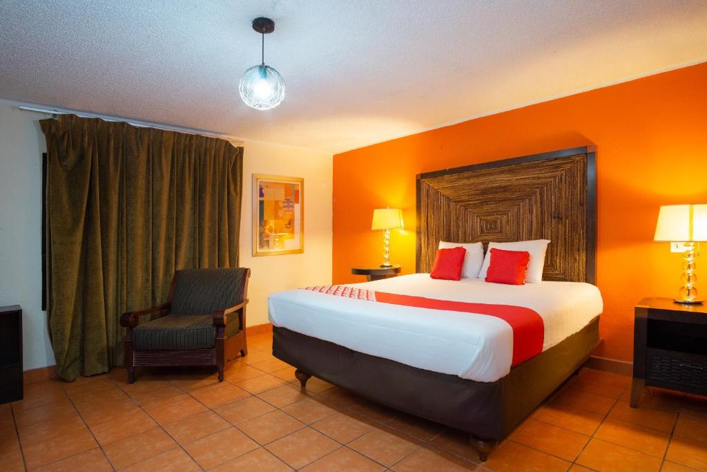 a hotel room with a large bed and a chair at OYO Hotel Hacienda Don Luis, Rosarito in Rosarito