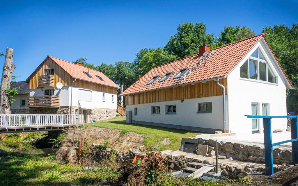 a white house with a wooden roof next to a building at WG Ragöser Wasserrad in Sandkrug