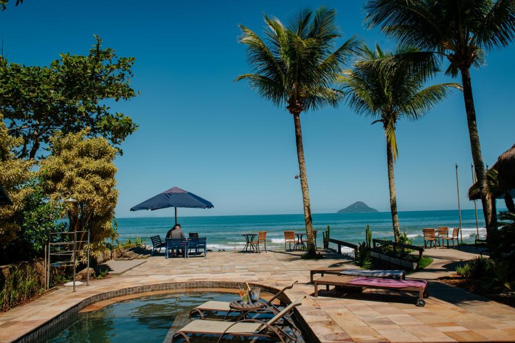 een zwembad op het strand met palmbomen en de oceaan bij Chez Louise et Louis Pé na Areia in Juquei