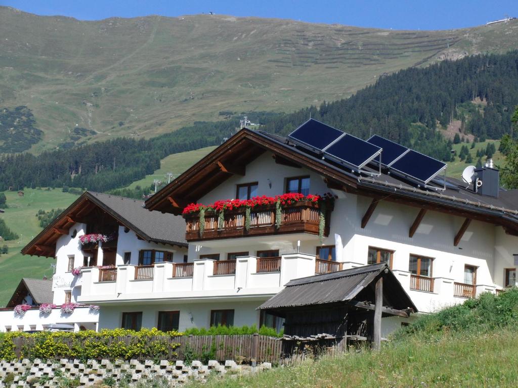 un bâtiment blanc avec des panneaux solaires sur le toit dans l'établissement Apart Alpenstern, à Fiss