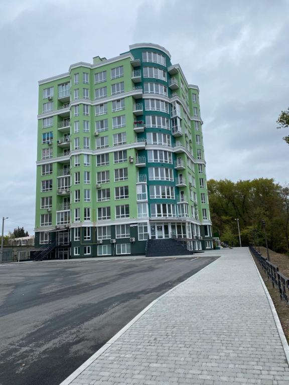 ein großes, grünes Apartmenthaus auf einem Parkplatz in der Unterkunft Magic Days Apartments in Tschernihiw