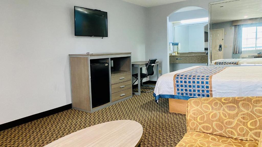 a hotel room with two beds and a flat screen tv at Moonlight Inn and Suites in Houston