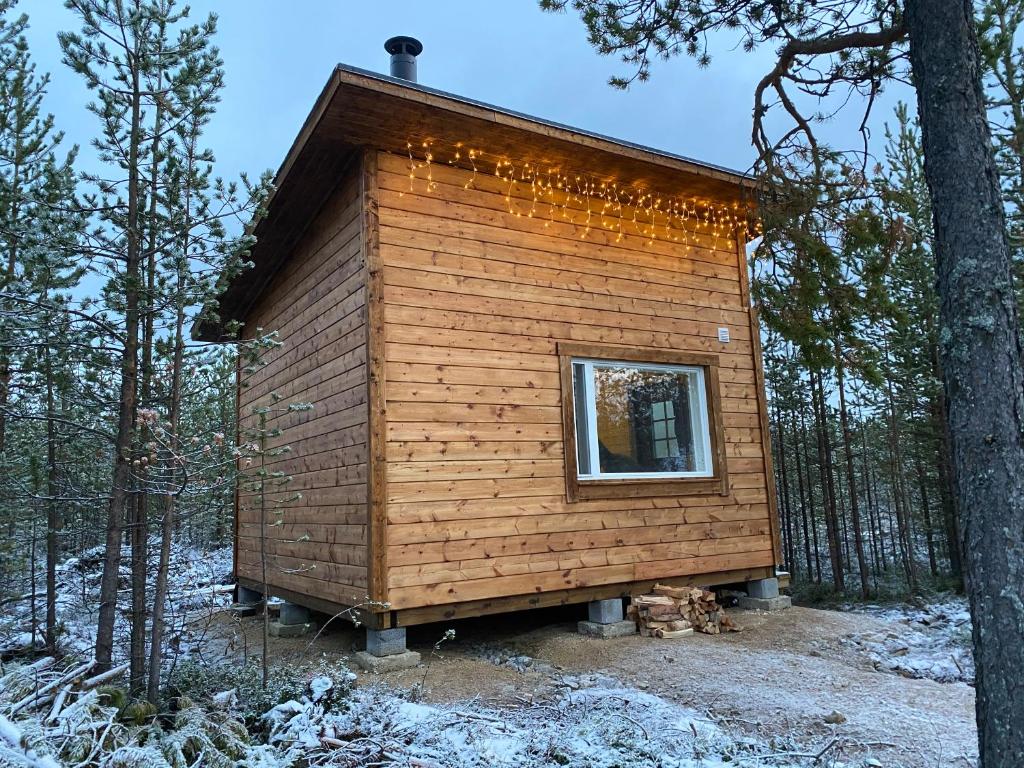 Una pequeña casa en el bosque con una ventana en Aurora Husky Hut, en Inari