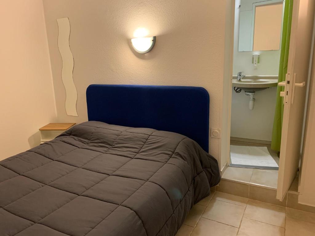 - une chambre avec un lit bleu et un lavabo dans l'établissement Hotel Macon la Salle, à Mâcon