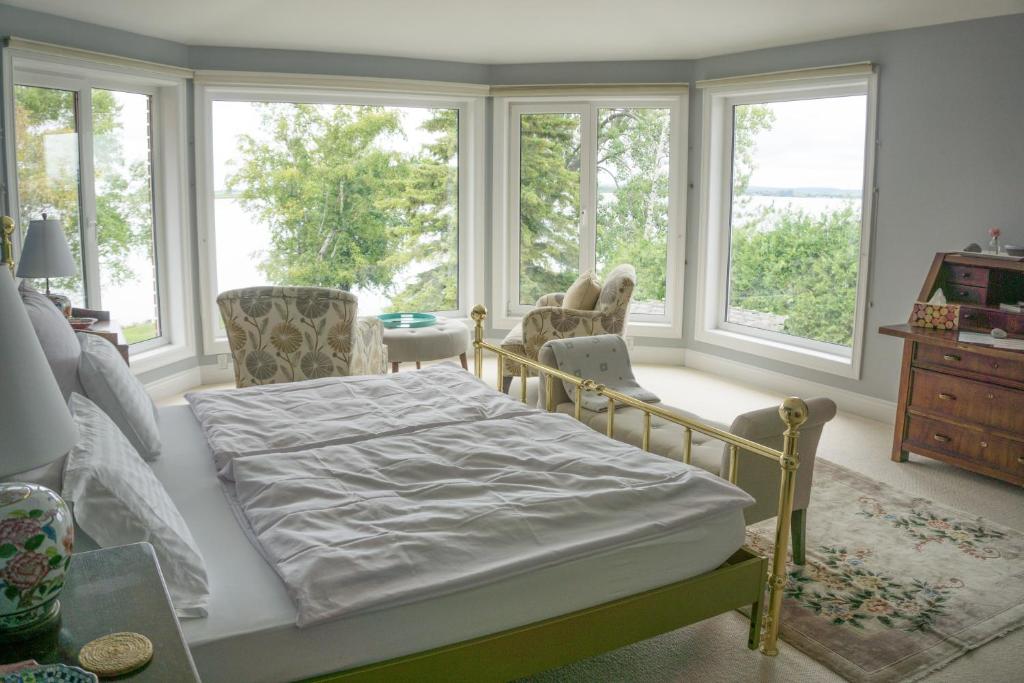 a bedroom with a bed and windows and a table at The Empty Nest B & B in Carrying Place