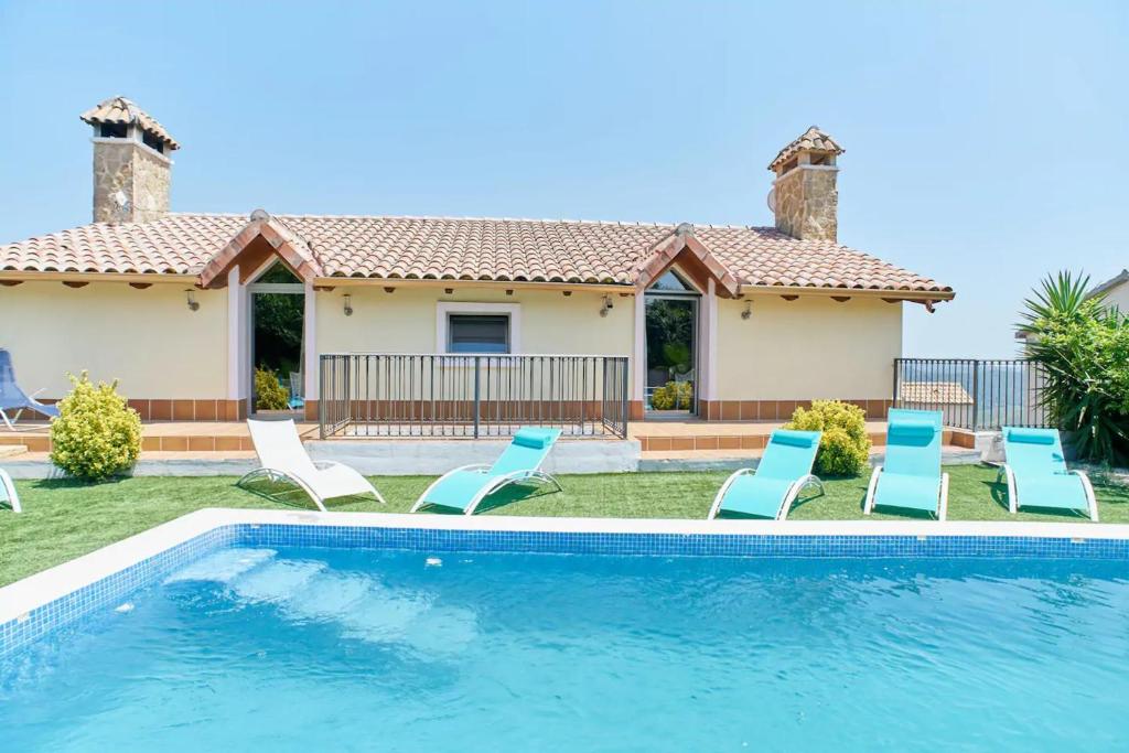 una piscina con sillas y una casa en 6 bedrooms villa with sea view private pool and jacuzzi at Olivella en Olivella